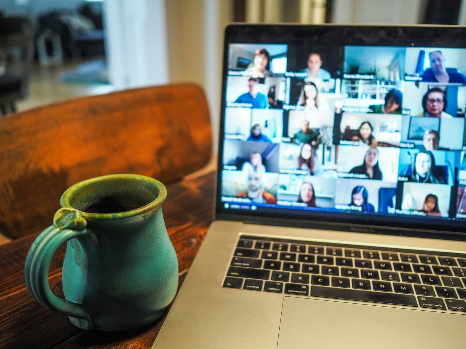 Laptop on a kitchen table showing a video call next to a coffee mug